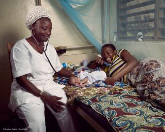 A nurse at a health center in Athiémé,  Benin, examines a newborn beside the  proud mother. © Stephan Gladieu / World Bank