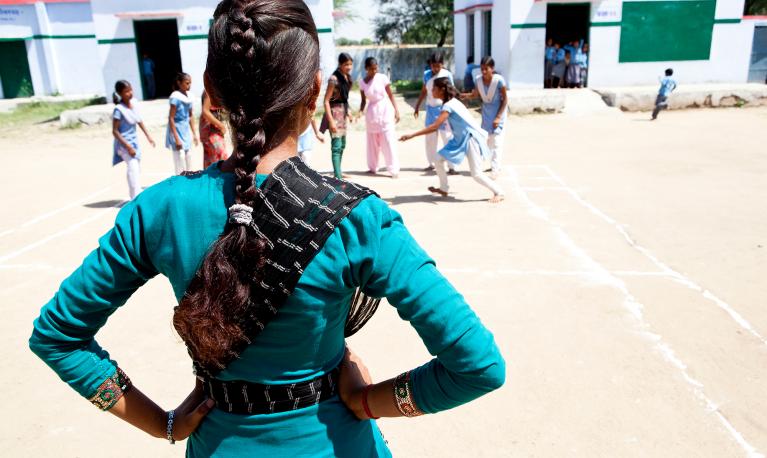 The back of a school girl in India looking at her friends in the playground. Credit: Charlotte Anderson