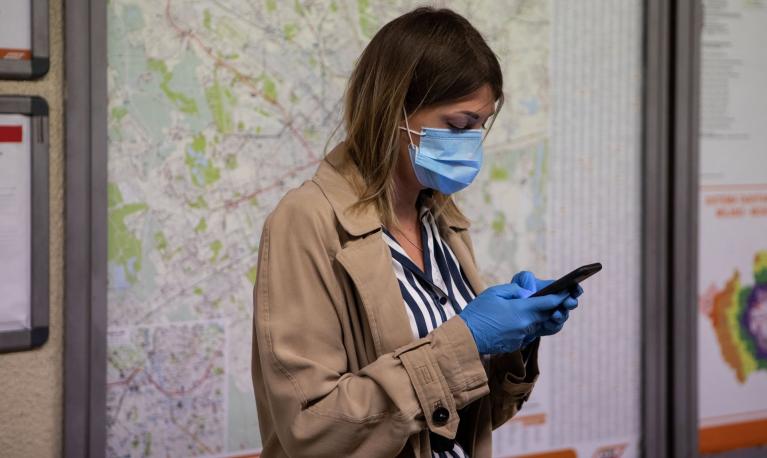A woman wearing a mask and gloves uses a mobile phone while waiting for an underground train in Milan, Italy. Photograph: Emanuele Cremaschi/Getty Images