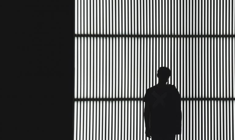Silhouette of a man against a slatted backdrop. © Nicholas Kwok/Unsplash