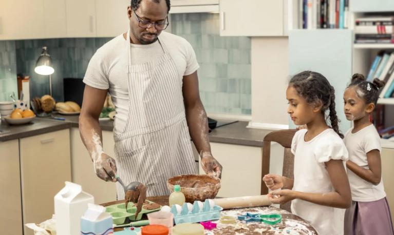 A father doing some home-baking with his daughters. © Viacheslav Iakobchuk/Alamy Stock Photo