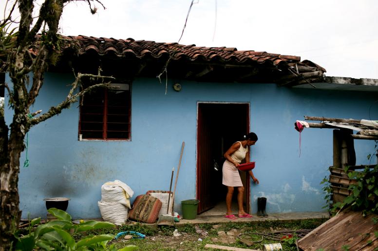 A woman outside her sky blue home near Santander, Colombia. © Charlotte Kesl / World Bank