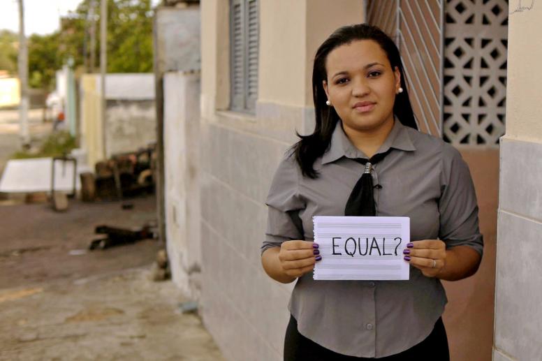 A Brazilian student holding a sign saying 'equal'. Credit: Romel Simon/World Bank