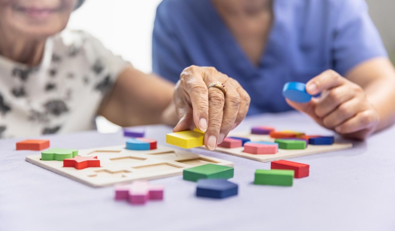 Caregiver and senior woman working on shape puzzles for dementia prevention © Toa55 | Shutterstock.com