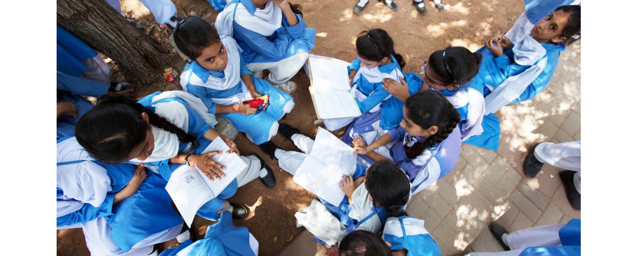 Schoolgirls at an Aahung partner school reading in the shade of a tree. © Aahung