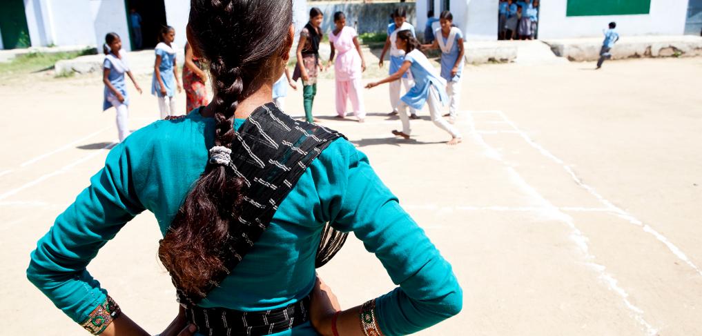 The back of a school girl in India looking at her friends in the playground. Credit: Charlotte Anderson