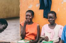 Lucy Agweto (far left), Christine Akwaso (far right), and their peers enjoy a meal together in Oditel, Uganda. © Brian Wolfe