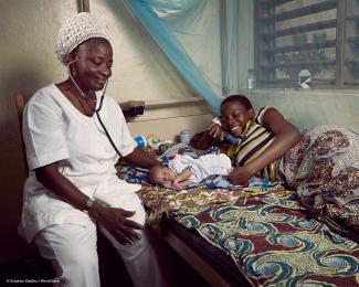 A nurse at a health center in Athiémé, Benin, examines a newborn beside the proud mother. © Stephan Gladieu / World Bank