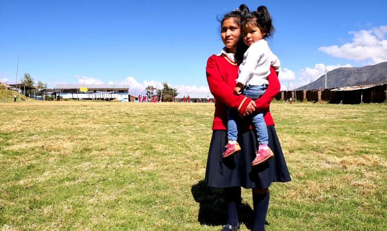 A school girls holds her younger sister. Credit: Visionaria