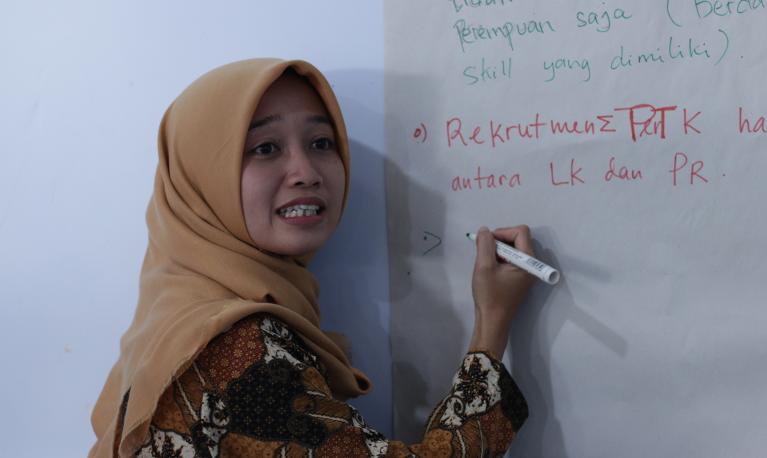 A participant writes notes on a white board at the convening