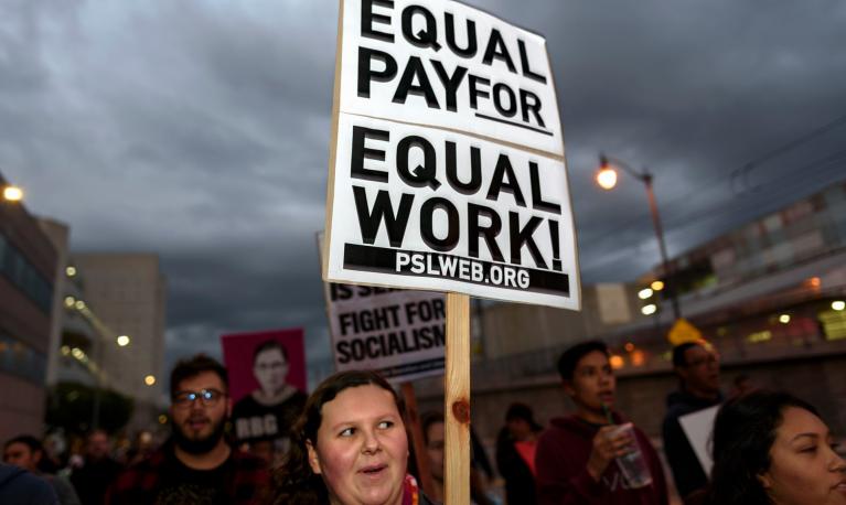 A woman holds a placard at a rally reading " Equal pay for equal work." Copyright Ronen Tivony/LightRocket/Getty Images"