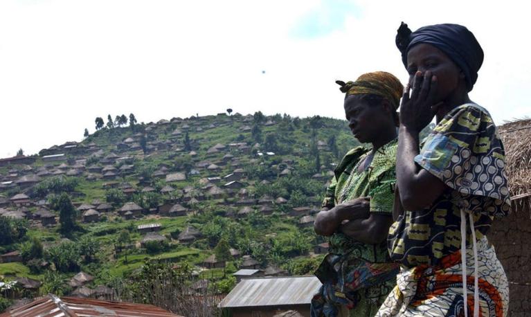 Two Congolese women with a village on a hill in the background. © Stephen Morrision/EPA