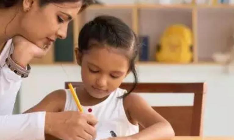 A mother helps her daughter to write a letter in India. Copyright: Times of India