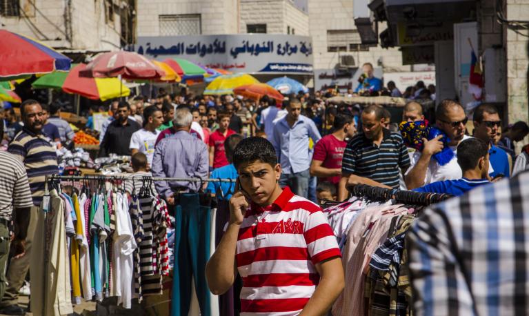 An adolescent on a mobile phone at a market in Ramallah, West Bank. Photo: Arne Hoel / World Bank