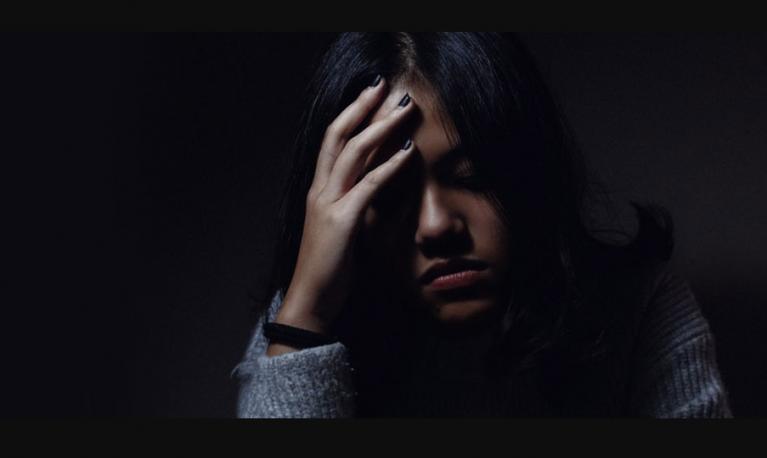 A women in the dark with her hand on her head. © University of Birmingham