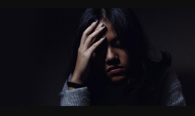 A women in the dark with her hand on her head. © University of Birmingham