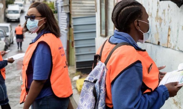 Women in face masks and orange tabards conducting door to door surveys. ©Guy Oliver / Alamy Stock Photo