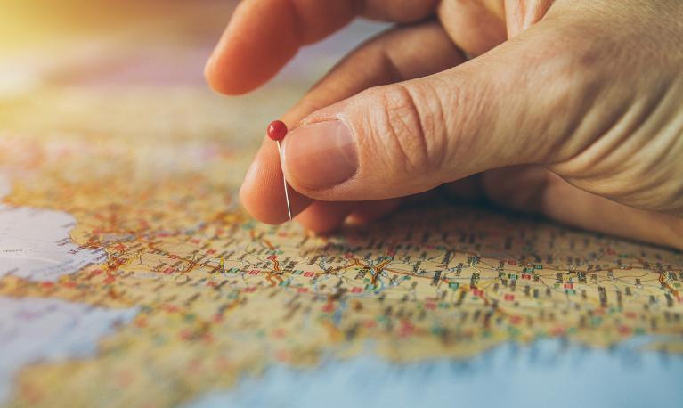 A hand putting a pin in a map.