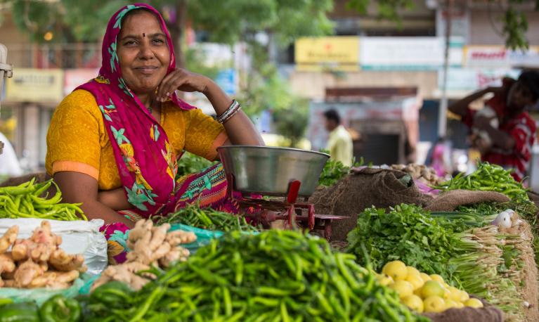 Choral Mauladia poses near by her cart where she sells vegetables at a local market.