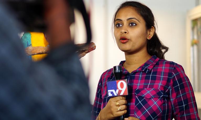 Female TV reporter covering live news in Hyderabad, India. Credit: Reddees / Shutterstock.com