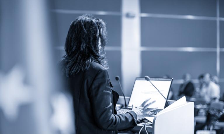 A female speaker at a conference ©Matej Kastelic / Shutterstock ID: 1156310920