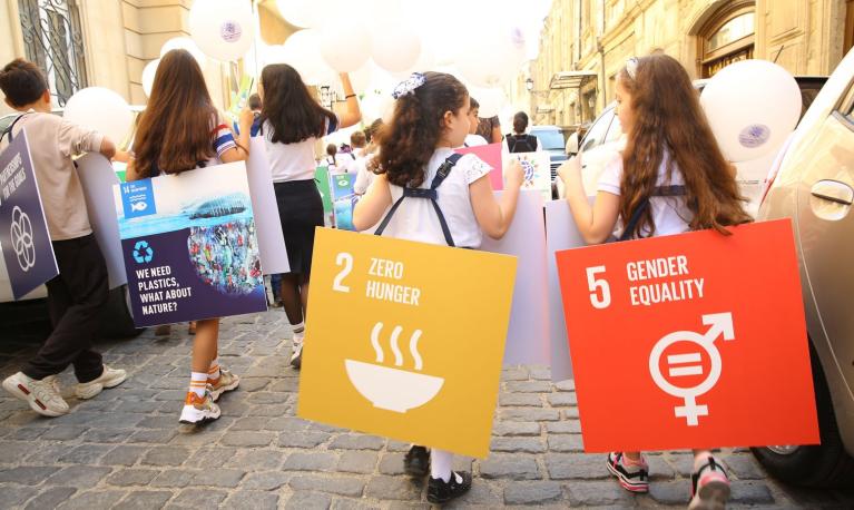 Children march with sustainable development goal placards © Adil Celebiyev StokPhoto