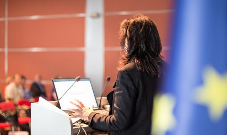 A female speaker at a political conference. ©  Matej Kastelic | Shutterstock ID: 1122952391
