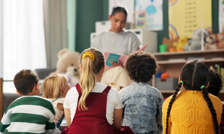A kindergarten with children and teacher reading a story © PeopleImages | Shutterstock ID: 2472680051