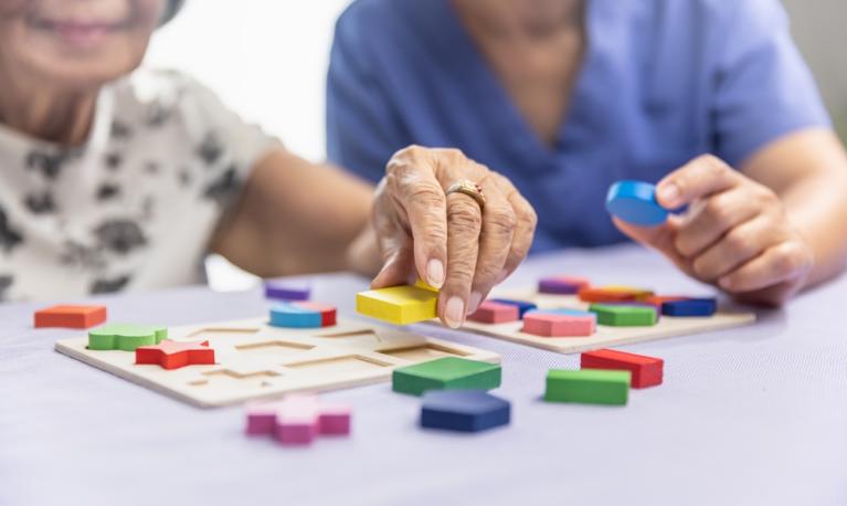 Caregiver and senior woman working on shape puzzles for dementia prevention © Toa55 | Shutterstock.com