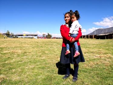 A school girls holds her younger sister. Credit: Visionaria