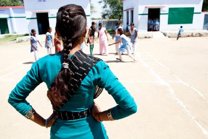 The back of a school girl in India looking at her friends in the playground. Credit: Charlotte Anderson