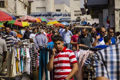 An adolescent on a mobile phone at a market in Ramallah, West Bank. Photo: Arne Hoel / World Bank