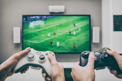 Hands operating video game controllers playing a football-base game. © REDPIXEL/shutterstock 537529714