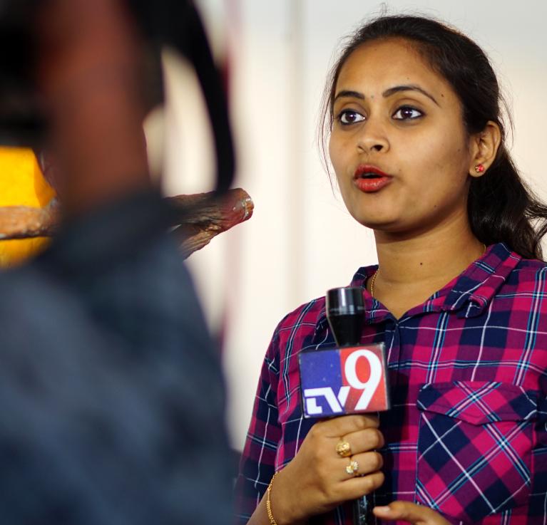 Female TV reporter covering live news in Hyderabad, India. Credit: Reddees / Shutterstock.com