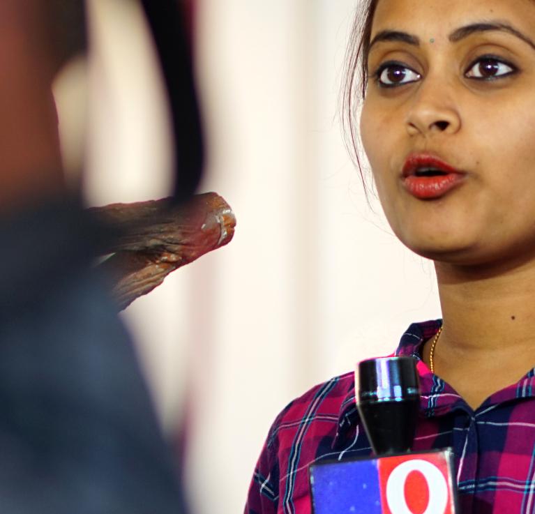 Female TV reporter covering live news in Hyderabad, India. Credit: Reddees / Shutterstock.com