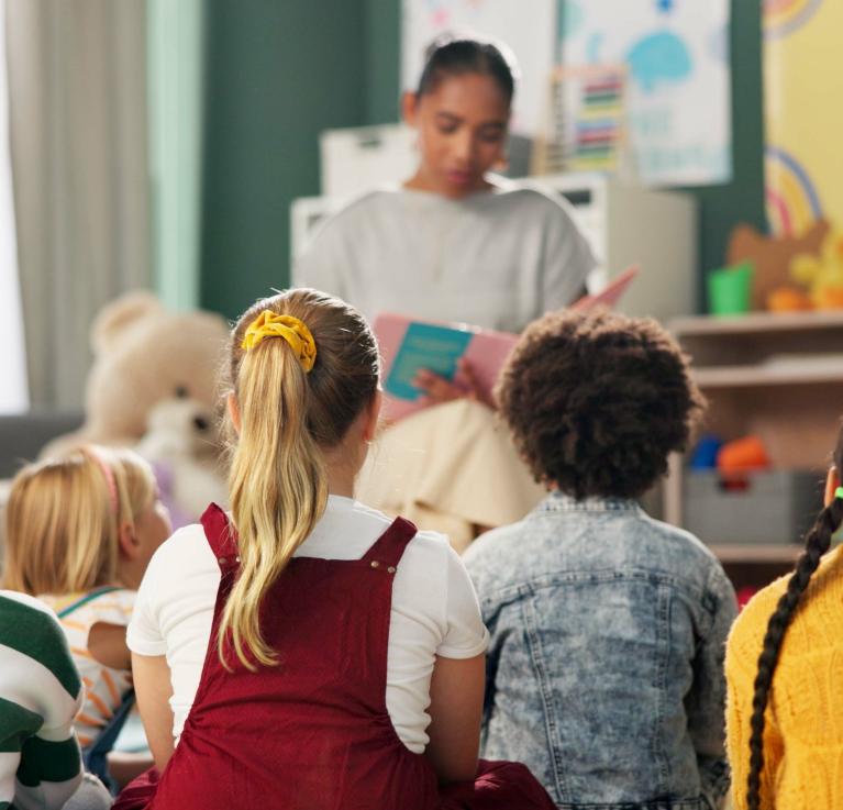 A kindergarten with children and teacher reading a story © PeopleImages | Shutterstock ID: 2472680051
