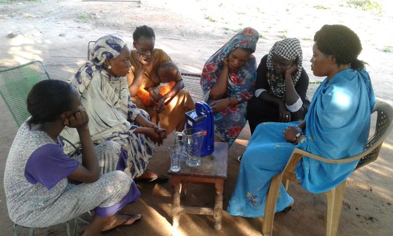 Members of a community listening club listen to and discuss the Life in Lulu programme as a group.  