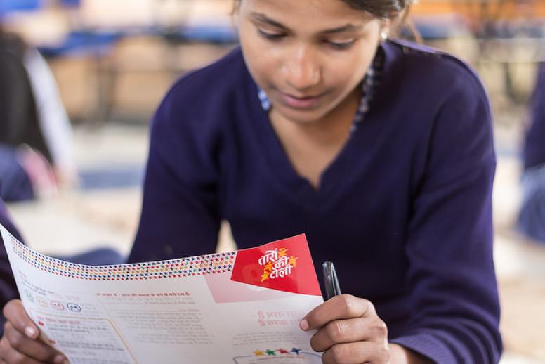 A girls reading her Taaron ki Toli worksheet